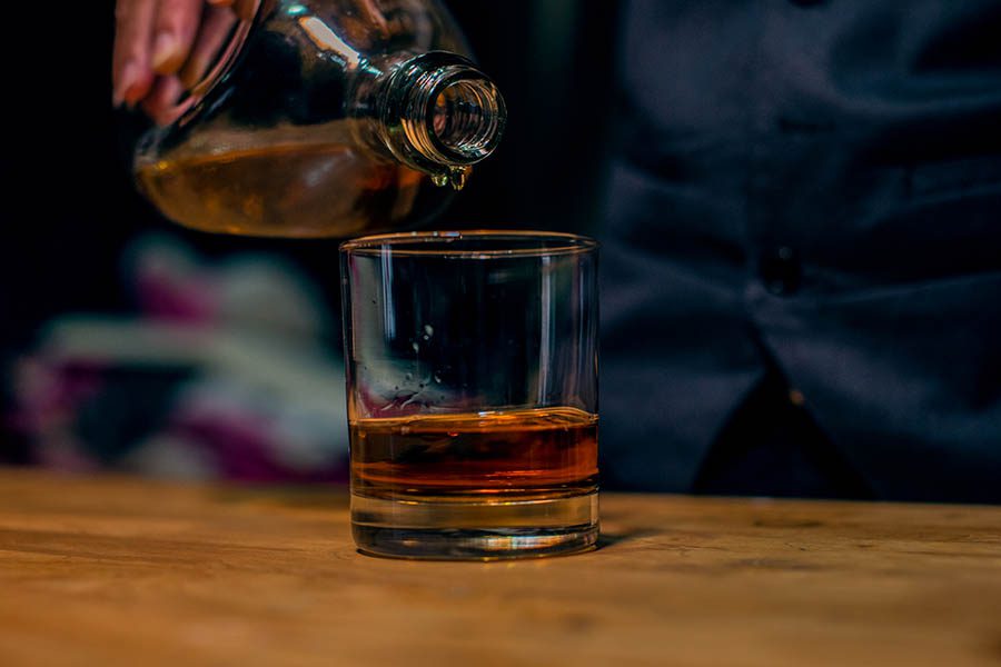 Distillery Insurance - Glass of Bourban Flowing into a Glass at a Bar